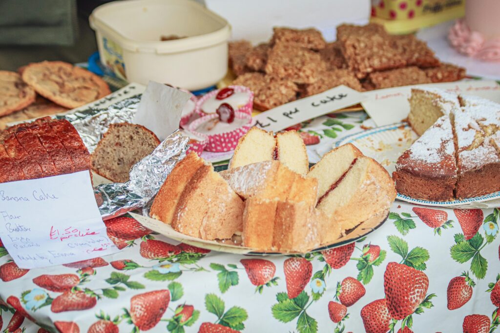 A variety of homemade cakes on a colorful table at a market stall.